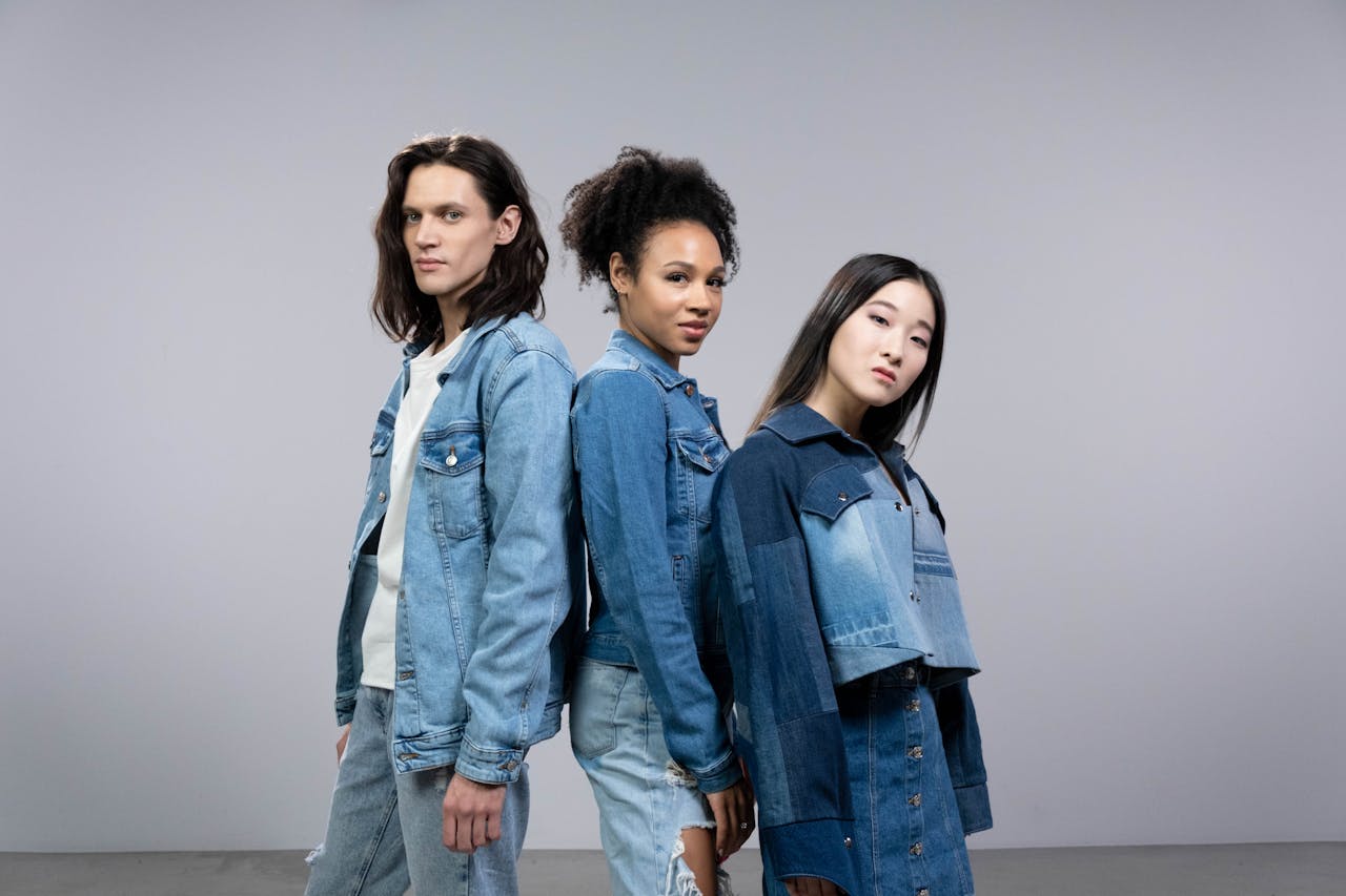 Three diverse models posing in stylish denim outfits in a studio setting.